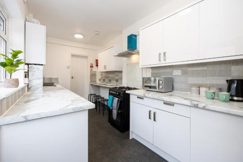 a white kitchen with white cabinets and appliances at M6 Guest House in Manchester