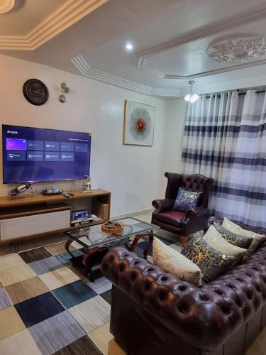 a living room with a leather couch and a flat screen tv at Natako Apartments in Apenkwa