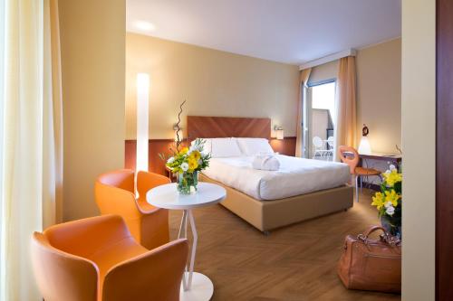 ミラノにあるUNAHOTELS Mediterraneo Milanoのベッド、テーブル、椅子が備わるホテルルームです。