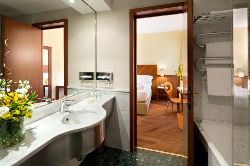 un baño de hotel con lavabo y un dormitorio en UNAHOTELS Mediterraneo Milano en Milán