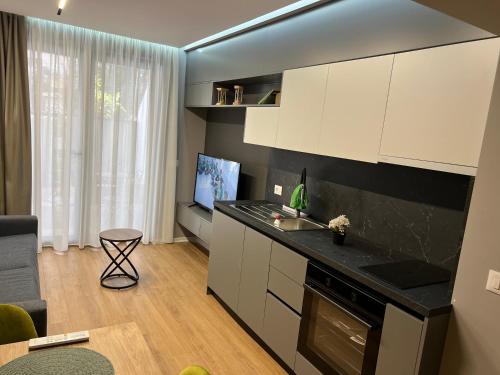 uma cozinha com armários brancos e uma sala de estar em Dan apartment Tirana em Tirana