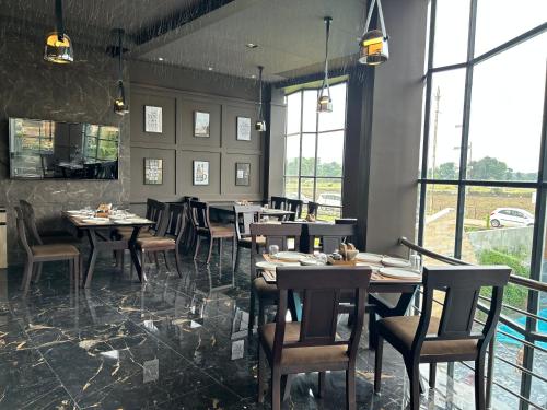 a dining room with tables and chairs and windows at The Sky Imperial Sethji Ni Wadi in Indore
