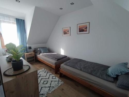 Sala de estar con 2 camas y mesa en Klimatyczny Domek - całoroczny, en Rydzewo
