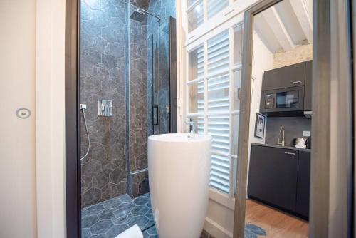 La salle de bains est pourvue d'une douche, d'une baignoire blanche et d'un lavabo. dans l'établissement CIA - CENTRAL LE MARAIS, à Paris