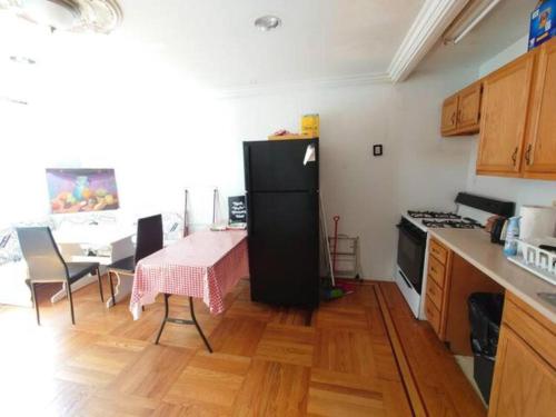 eine Küche mit einem Tisch und einem schwarzen Kühlschrank in der Unterkunft Fawlty Towers in Williamsburg in Brooklyn