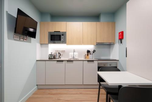 a kitchen with white cabinets and a table with chairs at Coleman Court Summer Apartments in Cork