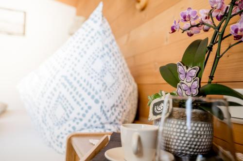 a table with a cup of coffee and a vase with purple flowers at Landhaus Geisler in Tux