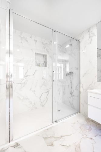 a bathroom with a shower with white marble walls at VIVA Serralves Vintage House in Porto