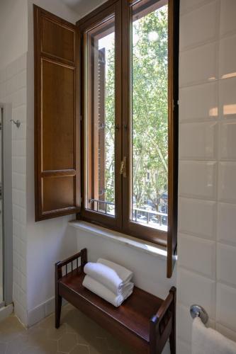 a bench in a bathroom with a window and towels at Casa I Cappuccini in Rome