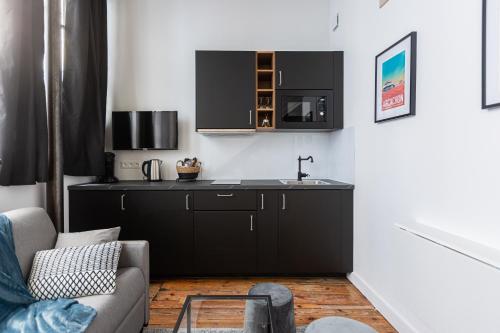 - une cuisine avec une armoire noire et un évier dans l'établissement Le Maupassant - Appt en mezzanine, à Bordeaux