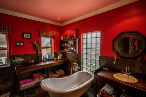 Łazienka z czerwonymi ścianami, wanną i umywalką w obiekcie Royal Alfred Marina w mieście Port Alfred