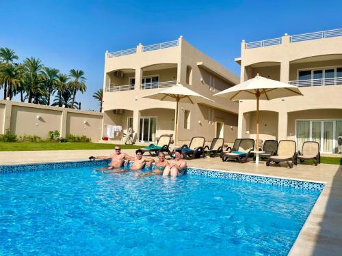 a group of people sitting in a swimming pool at Royal Nile Villa - Pool View Apartment 1 in Luxor