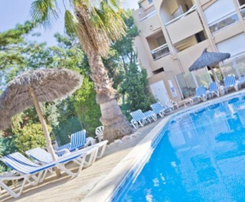 una piscina con sillas y sombrillas junto a un hotel en Studio/f1bis à 50 m de la plage en Argelès-sur-Mer