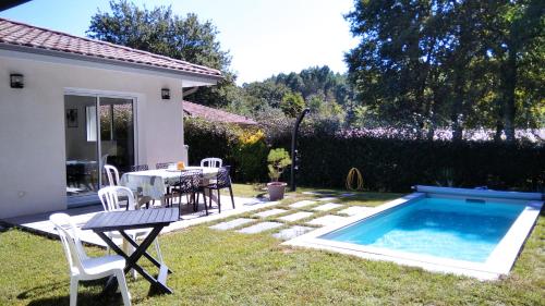 a backyard with a table and a swimming pool at Maison Solyselva Piscine- Proche océan- Climatisée in Saubion