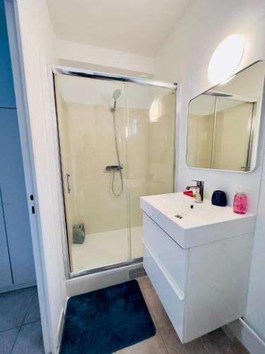 une salle de bain blanche avec une douche et un lavabo dans l'établissement Superbe studio proche Disney, à Champs-sur-Marne