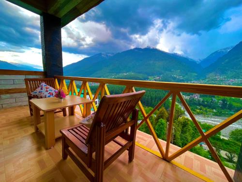 Un balcón con 2 sillas y una mesa con vistas. en Bentenwood Resort - A Beutiful Scenic Mountain & River View, en Manali