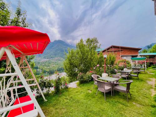 a group of tables and chairs on a lawn with a mountain at Bentenwood Resort - A Beutiful Scenic Mountain & River View in Manāli