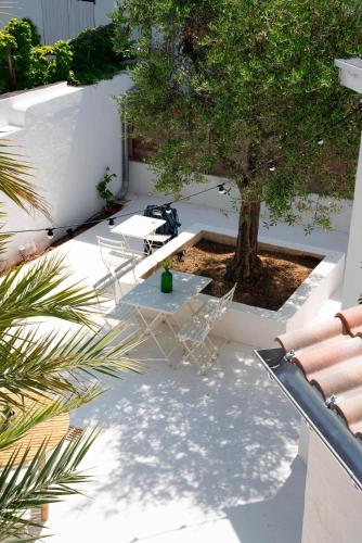 a patio with chairs and a table and a tree at Hôtel Casa Marina in Saintes-Maries-de-la-Mer