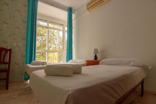 two beds in a room with a window at RentalSevilla Centrico Apartamento junto al Guadalquivir con Parking coche mediano in Seville