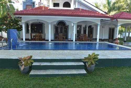 a swimming pool in front of a house at Sri Ra'anana Villa in Marawila