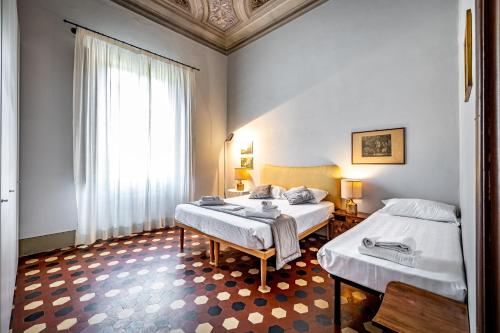a hotel room with two beds and a window at Roommo D'Azeglio in Florence