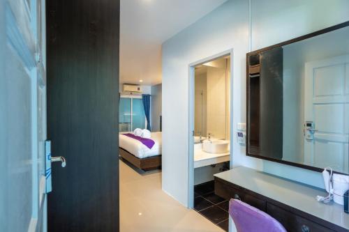 a bathroom with a television and a bedroom with a bed at The Great @Patong Hotel in Patong Beach
