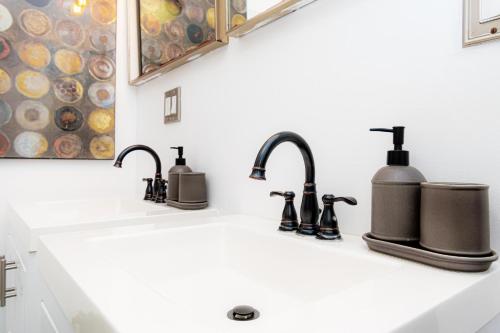 a bathroom sink with three soap dispensers on it at Luxury in the Heart of Brooklyn in Brooklyn