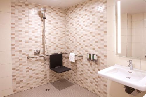a bathroom with a sink and a shower with a mirror at Hampton By Hilton Munich City Center East in Munich