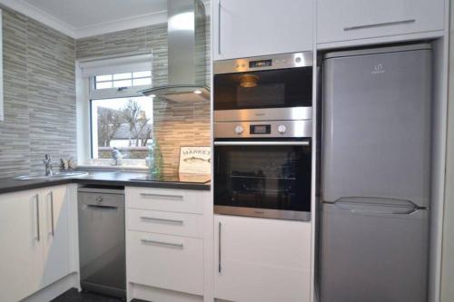 uma cozinha com um forno de aço inoxidável e frigorífico em Ideally Located Modern Flat em Troon