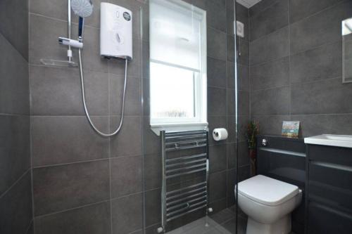 uma casa de banho com um chuveiro, um WC e uma janela. em Ideally Located Modern Flat em Troon