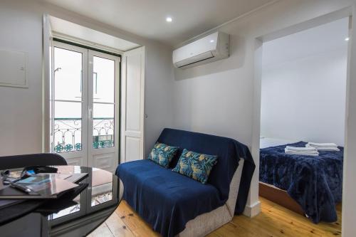 uma sala de estar com uma cadeira azul e uma cama em 133 B - My lovely house in Alfama with AC em Lisboa