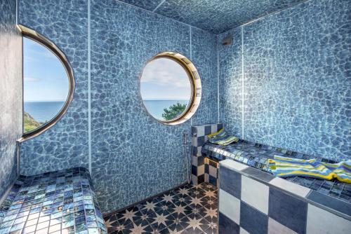 a bathroom with blue tiled walls and two windows at Cormorant in Torpoint