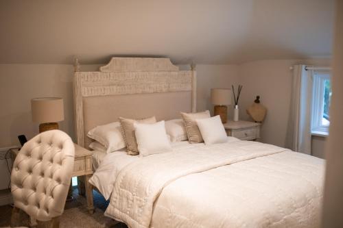 a bedroom with a large white bed and a chair at The Lodge in Rempstone