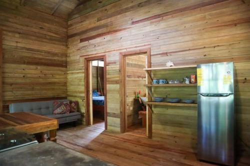 Jungle beach 2 bedroom cottage في بوكاس تاون: مطبخ بجدران خشبية وثلاجة في الغرفة