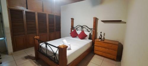 a bedroom with a bed with red pillows and a dresser at Kartagus Guest House in San Salvador