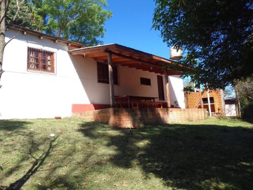 una pequeña casa blanca con porche en un patio en Casa del Río en Puerto Iguazú