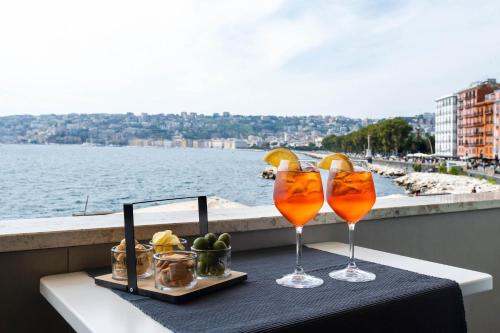 two glasses on a table with a view of the water at Imperatrice Suites in Naples