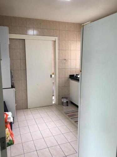 a kitchen with a white door and a tiled floor at Apartamento Compartilhado Quarto 3 Oktoberfest in Blumenau