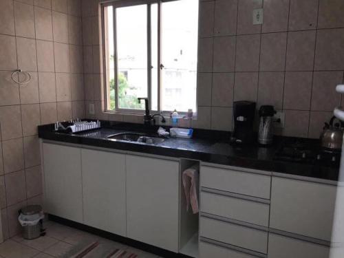 a kitchen with a sink and a window at Apartamento Compartilhado Quarto 3 Oktoberfest in Blumenau