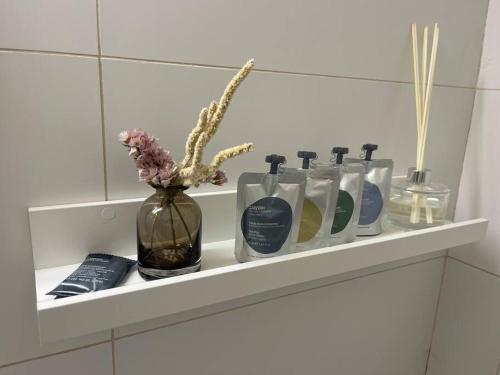 a shelf with a row of bottles and a vase with flowers at Bright and Cozy Bauhaus Gem in Ra‘ananna