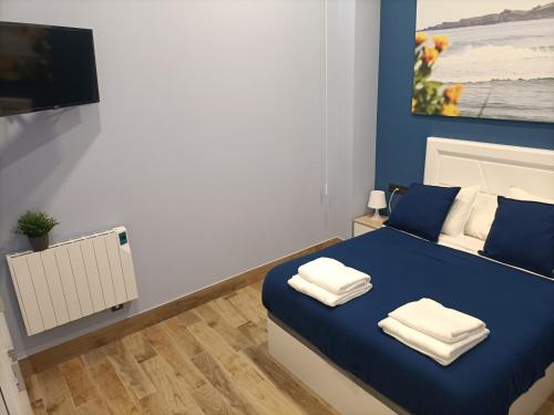 a bedroom with a blue bed with towels on it at Apto Izaro -Parking Gratis, Reformado- Gaztelugatxe y Gastronomía -Familias y Pareja in Bermeo