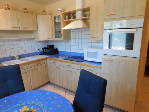 a kitchen with wooden cabinets and blue chairs at Ile Oléron Près du port de La Cotinière 2 pers. Plage et océan à 50 m in Saint-Pierre-dʼOléron