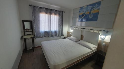 a small bedroom with a white bed and a window at La Font Lovely apartment LEstartit 400 meter from the beach in L'Estartit