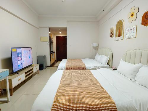 Cette chambre comprend 2 lits et une télévision à écran plat. dans l'établissement Guangzhou Boya Aparthotel Pazhou Exhibition Center - Next to Exit D of Wanshengwei MTR Station, à Canton