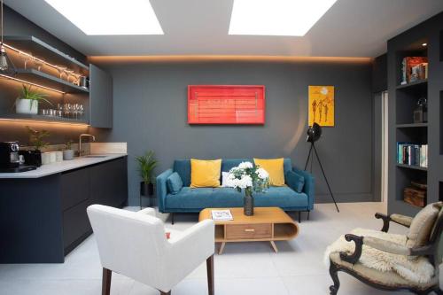 uma sala de estar com um sofá azul e almofadas amarelas em Stunning, architecturally designed Garden Studio with Parking em Londres
