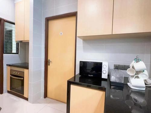 a kitchen with a black counter top and a microwave at The Floorspace Imperial Suites Apartment 2 in Kuching
