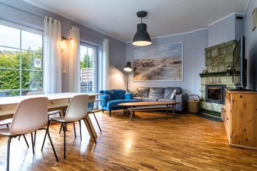 a living room with a table and chairs and a fireplace at Dom Kotwa in Karwia