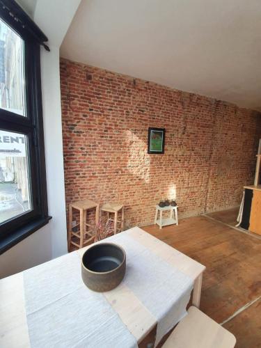 een kamer met een bakstenen muur en een kom op een tafel bij Den Gulden Hoorn in Antwerpen
