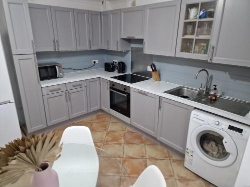 cocina con armarios blancos y lavadora en What a great location in Bromley with 4 bedrooms!, en Bromley