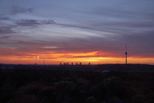 a sunset over a city with a tv tower at VILNIUS PARK PLAZA HOTEL, Restaurant & Terrace, Panorama Bar, Conference & Banquet Center in Vilnius